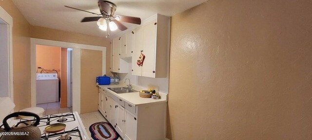 kitchen featuring light countertops, a sink, washer / dryer, white gas stove, and ceiling fan