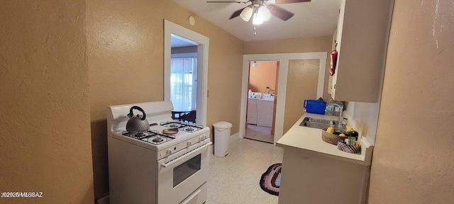 kitchen featuring light countertops, a sink, white range with gas stovetop, light floors, and ceiling fan