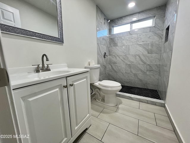 full bath with toilet, vanity, baseboards, and tiled shower