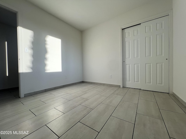 unfurnished bedroom with a closet and baseboards