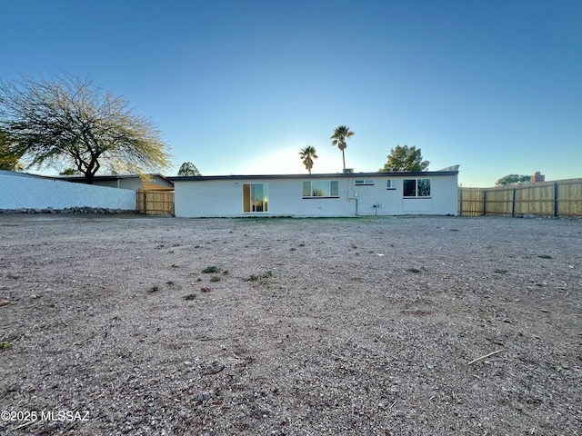 rear view of property with concrete block siding and fence