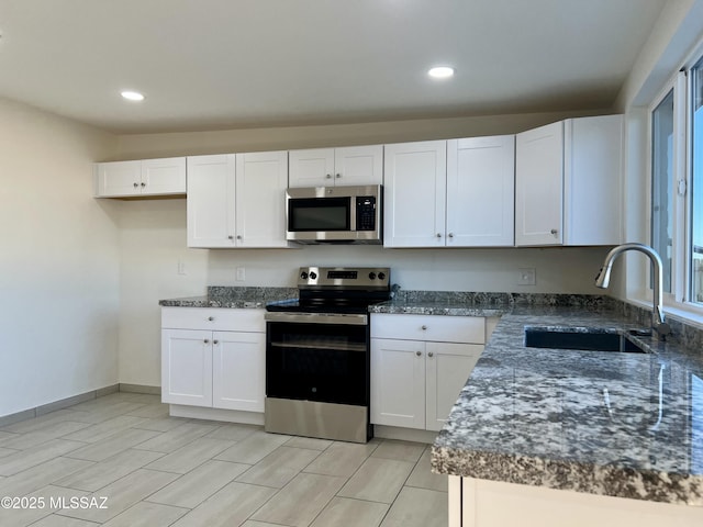 kitchen featuring a sink, white cabinetry, appliances with stainless steel finishes, dark stone countertops, and recessed lighting