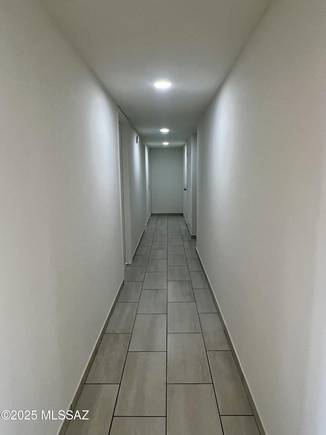 hall with light tile patterned flooring and baseboards