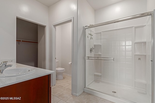 bathroom with toilet, tile patterned floors, a sink, a stall shower, and double vanity
