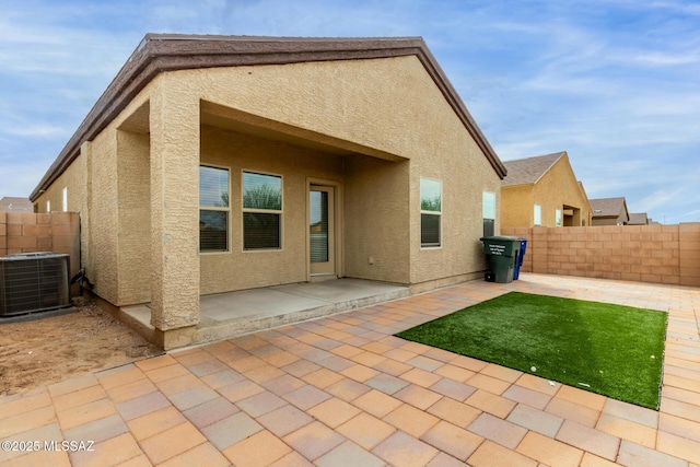 rear view of property featuring cooling unit, stucco siding, fence, and a patio area