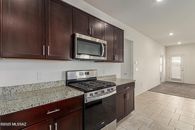 kitchen featuring light stone countertops, recessed lighting, appliances with stainless steel finishes, dark brown cabinetry, and light colored carpet
