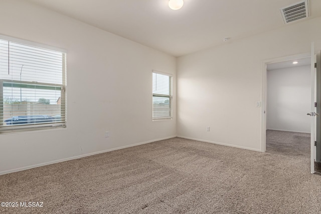 empty room featuring baseboards, visible vents, and carpet floors