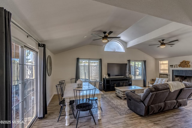 living room with wood finished floors, a tiled fireplace, and a ceiling fan