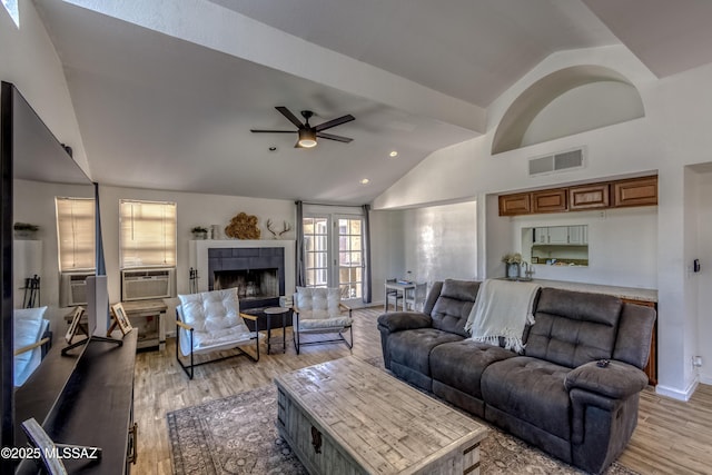 living area with visible vents, vaulted ceiling, a ceiling fan, and light wood finished floors