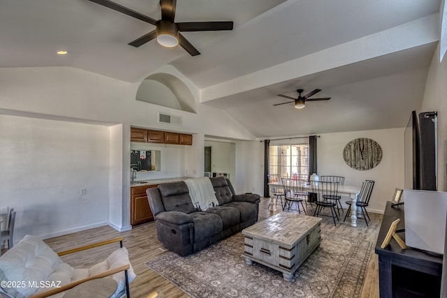 living room featuring vaulted ceiling, light wood-type flooring, baseboards, visible vents, and ceiling fan