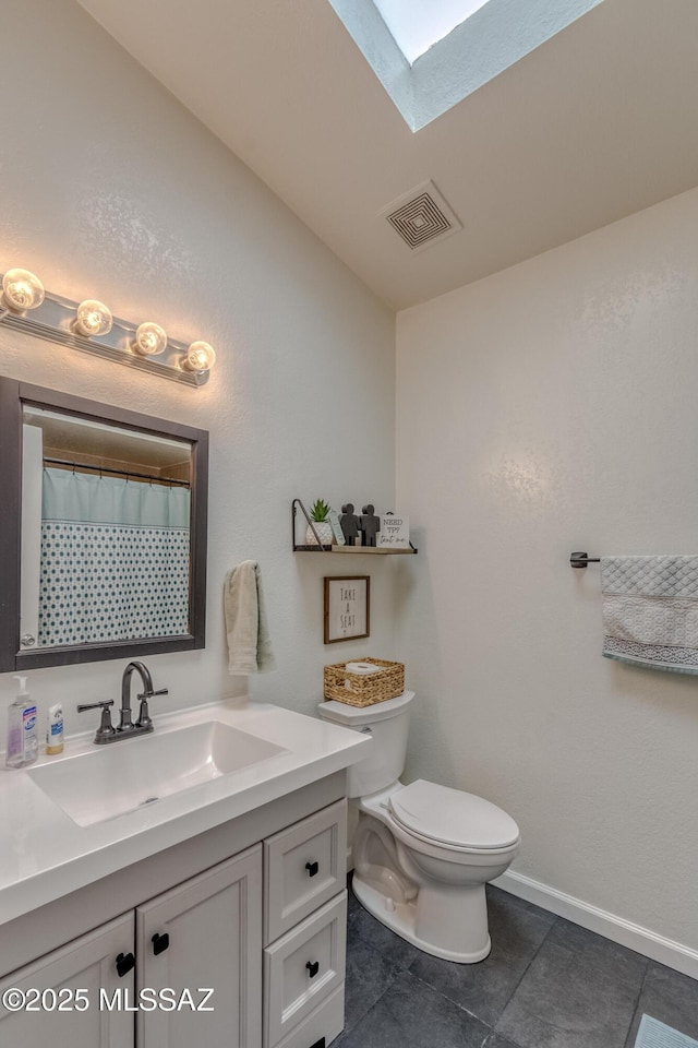 bathroom with toilet, vanity, a skylight, baseboards, and visible vents