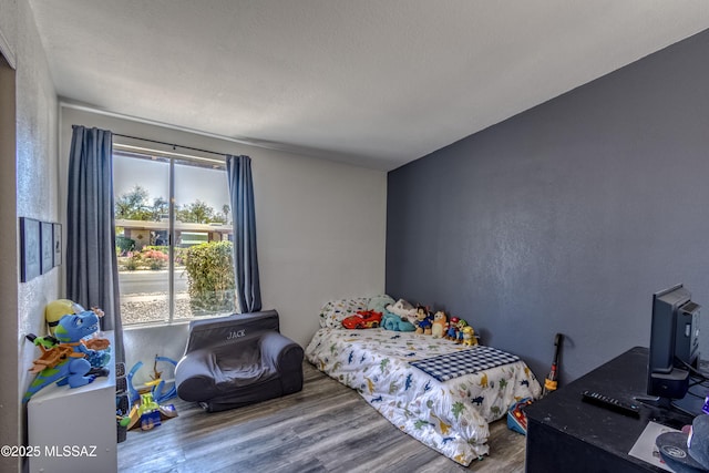 bedroom with a textured wall and wood finished floors