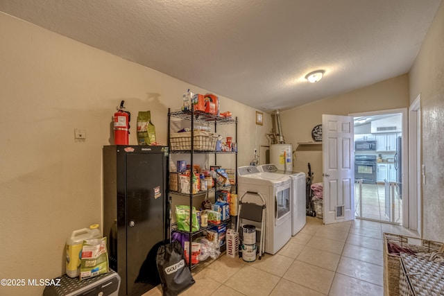 washroom featuring water heater, independent washer and dryer, a textured ceiling, light tile patterned flooring, and laundry area