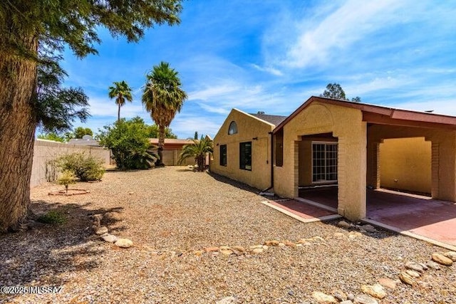 rear view of property with stucco siding and fence