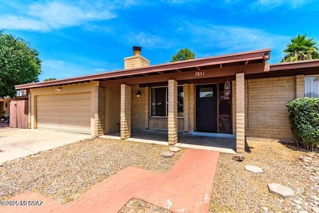 ranch-style house featuring driveway, an attached garage, and a chimney