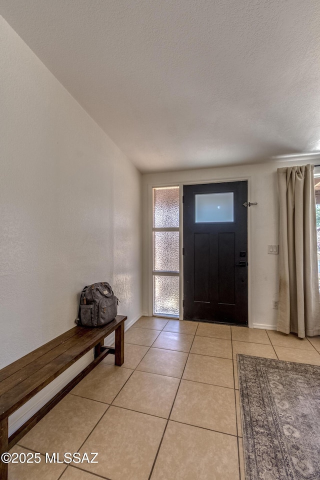foyer entrance featuring a textured ceiling and light tile patterned floors