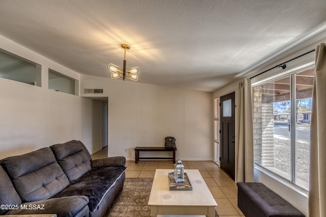 living room featuring a textured ceiling, visible vents, a chandelier, and light tile patterned floors