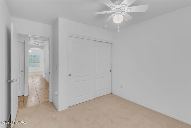 660 W Via Rosaldo, Green Valley, AZ 85614 - unfurnished bedroom with a closet, tile patterned floors, carpet flooring, a ceiling fan, and arched walkways