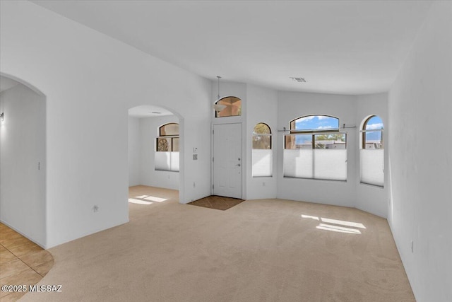 660 W Via Rosaldo, Green Valley, AZ 85614 - unfurnished living room featuring arched walkways, carpet flooring, and lofted ceiling