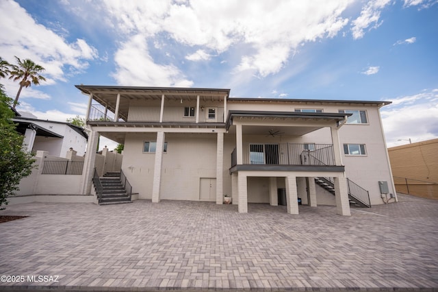 back of house featuring a ceiling fan, a balcony, and stairs