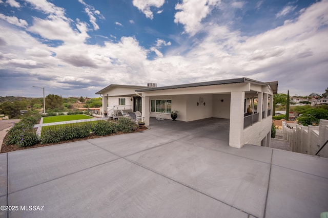 view of front of home with an attached carport, fence, and concrete driveway