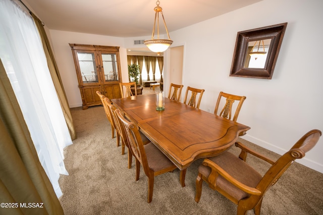 dining room featuring light colored carpet, visible vents, and baseboards