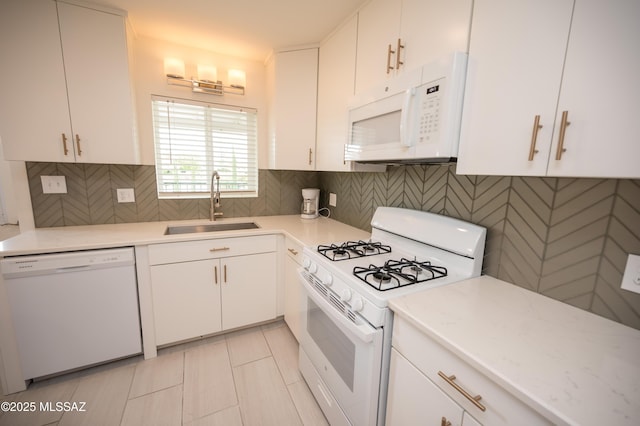 kitchen featuring light tile patterned flooring, white appliances, white cabinetry, a sink, and backsplash