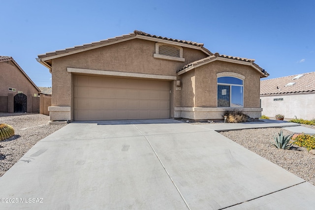 view of front facade with stucco siding, an attached garage, a tiled roof, and concrete driveway