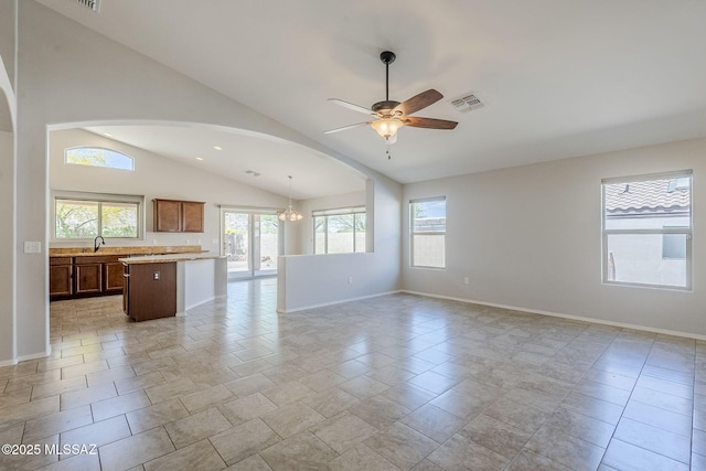 unfurnished living room featuring arched walkways, visible vents, baseboards, and ceiling fan with notable chandelier