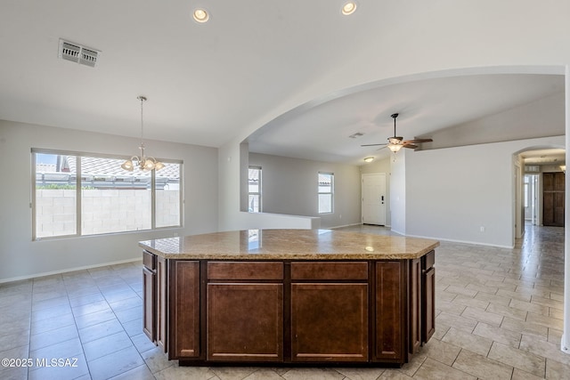 kitchen with arched walkways, dark brown cabinets, vaulted ceiling, visible vents, and ceiling fan with notable chandelier