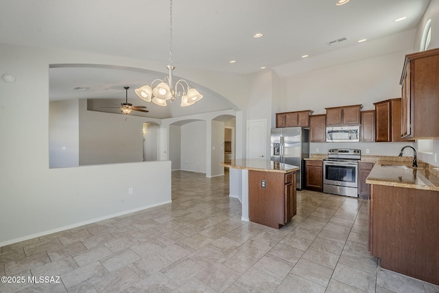 kitchen with a sink, open floor plan, arched walkways, appliances with stainless steel finishes, and visible vents