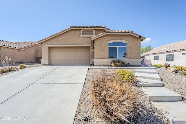 view of front facade featuring stucco siding, a tile roof, driveway, and a garage