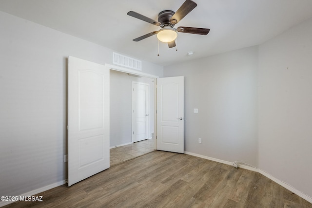 unfurnished bedroom featuring wood finished floors, visible vents, baseboards, and ceiling fan