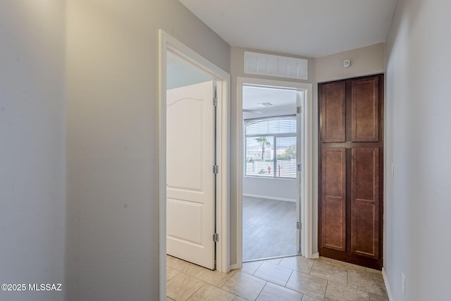 hall with baseboards, light tile patterned flooring, and visible vents