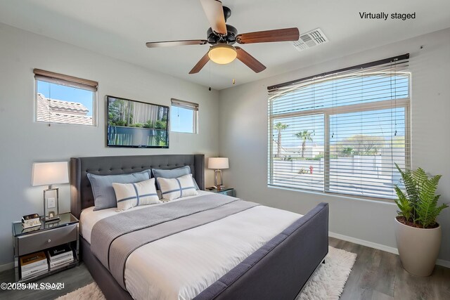 bedroom with visible vents, baseboards, wood finished floors, and ceiling fan