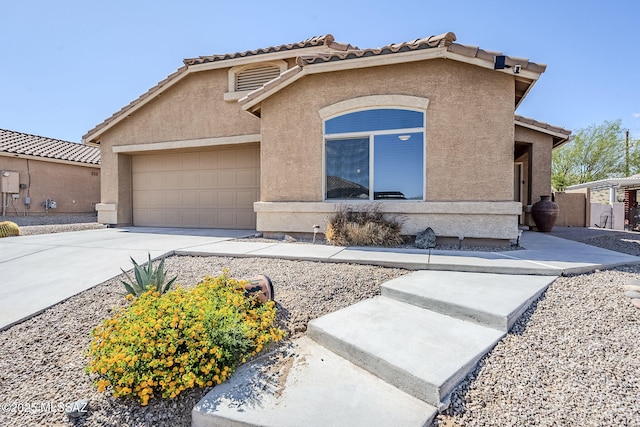 view of front facade with stucco siding, an attached garage, driveway, and a tile roof