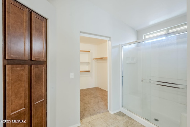 bathroom with tile patterned flooring, a walk in closet, and a stall shower