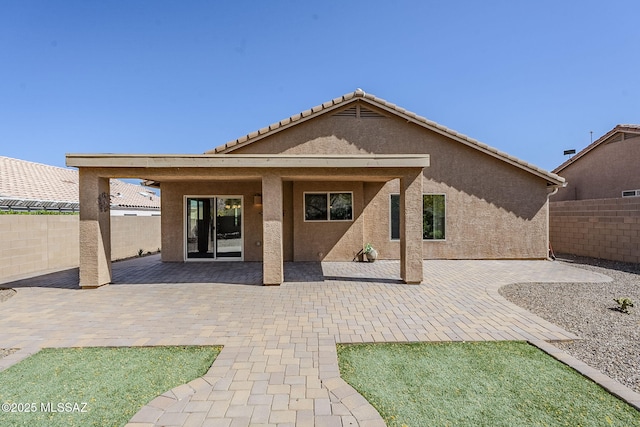rear view of property with a patio area, a fenced backyard, a tile roof, and stucco siding