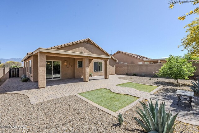 back of property featuring a patio area, a fenced backyard, a gate, and stucco siding