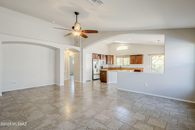unfurnished living room with vaulted ceiling, a ceiling fan, a sink, baseboards, and visible vents