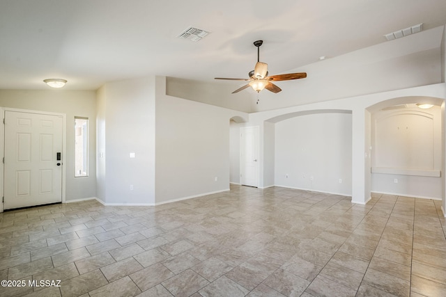 unfurnished living room featuring ceiling fan, arched walkways, visible vents, and baseboards