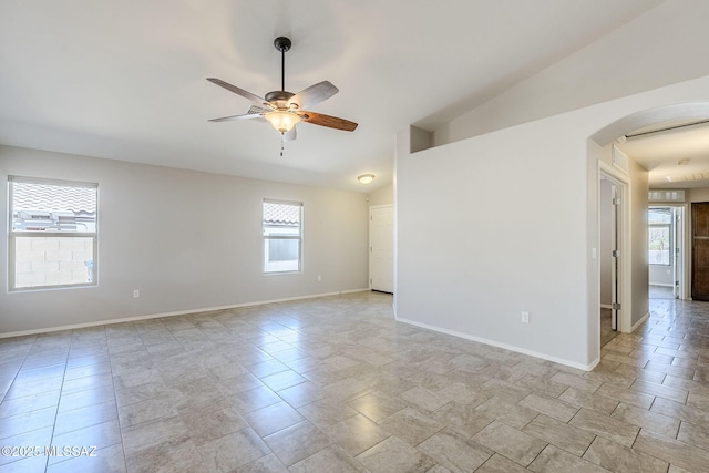 empty room with arched walkways, lofted ceiling, baseboards, and ceiling fan