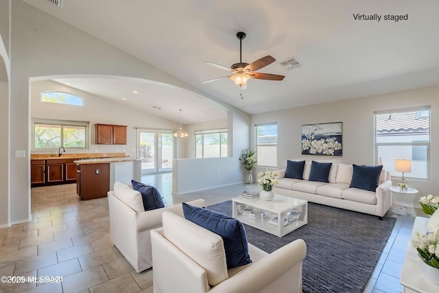 living room with ceiling fan, arched walkways, visible vents, and plenty of natural light