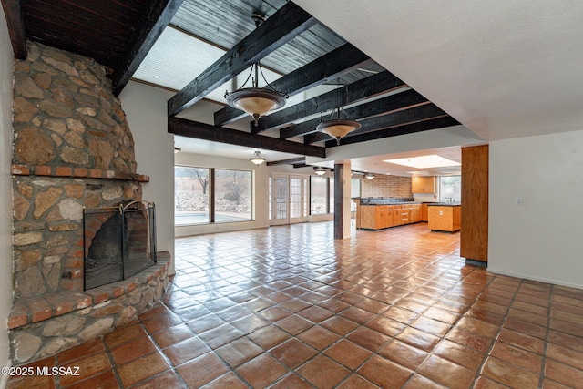 5374 E Spring Rd, Hereford, AZ 85615 - unfurnished living room featuring a stone fireplace and beamed ceiling