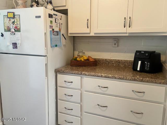 kitchen featuring white cabinetry and freestanding refrigerator