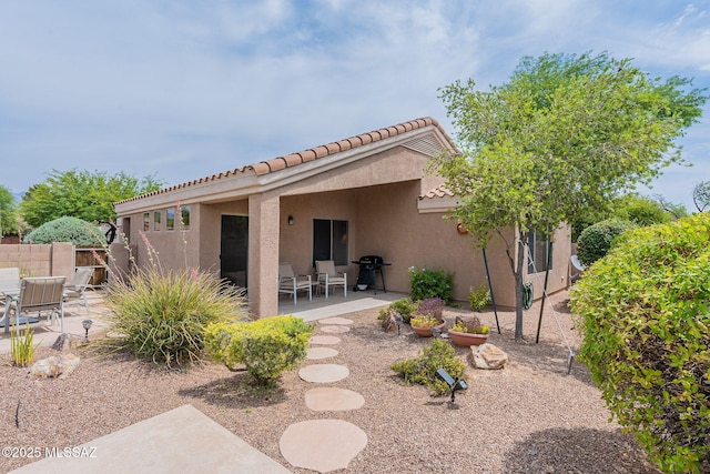 back of house featuring fence, a tile roof, a patio area, and stucco siding