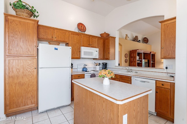 kitchen with white appliances, light countertops, arched walkways, a sink, and light tile patterned floors