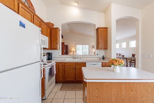 kitchen featuring white appliances, light countertops, arched walkways, a sink, and vaulted ceiling