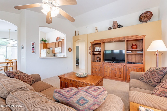 living area featuring arched walkways, ceiling fan, and light carpet
