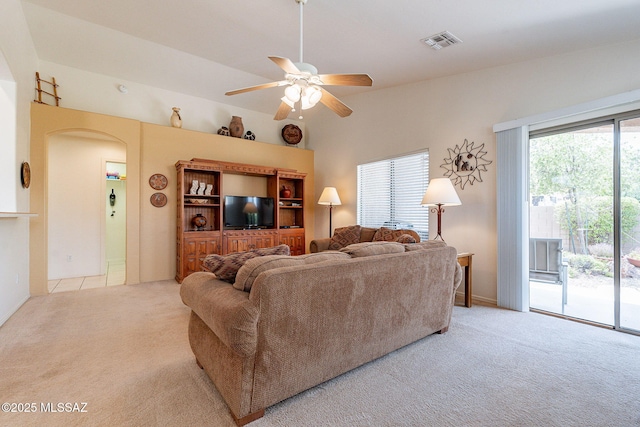living room featuring light colored carpet, a ceiling fan, arched walkways, and visible vents